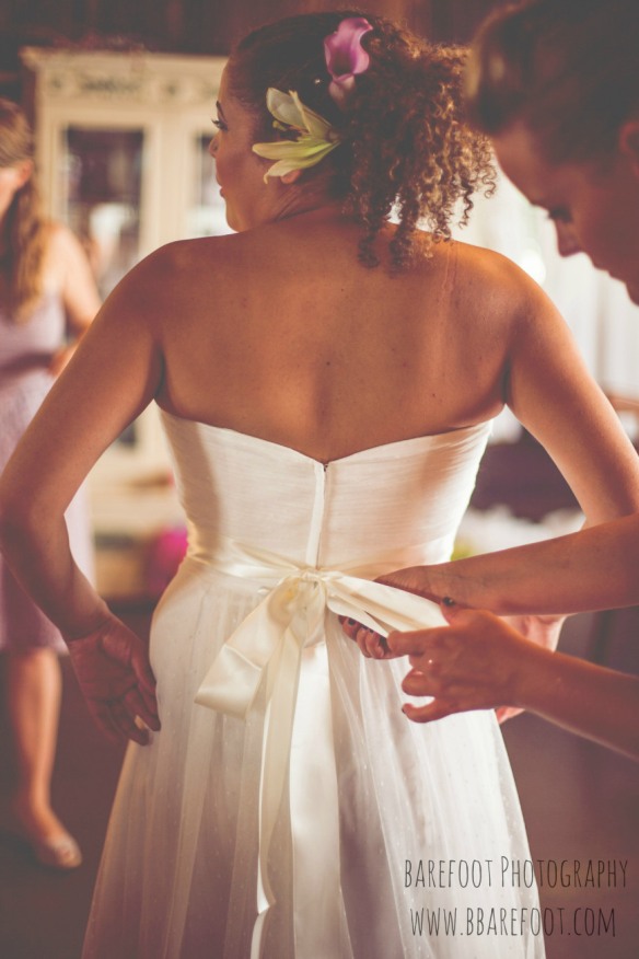bride getting bow tied on wedding dress